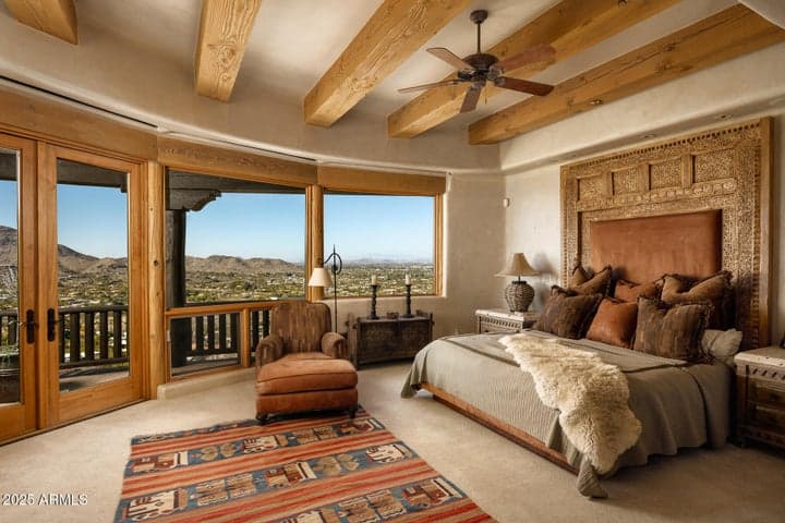 Wake up to sweeping views of Paradise Valley in this elegant primary suite. Hand-carved headboard detailing, exposed beam ceilings, and direct balcony access create a resort-like feel with timeless desert charm.