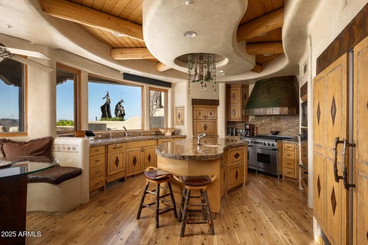 This custom chef’s kitchen boasts a large granite island, high-end stainless steel appliances, and handcrafted wood cabinetry. Unique ceiling detail, built-in seating, and panoramic mountain views complete this one-of-a-kind gourmet space.