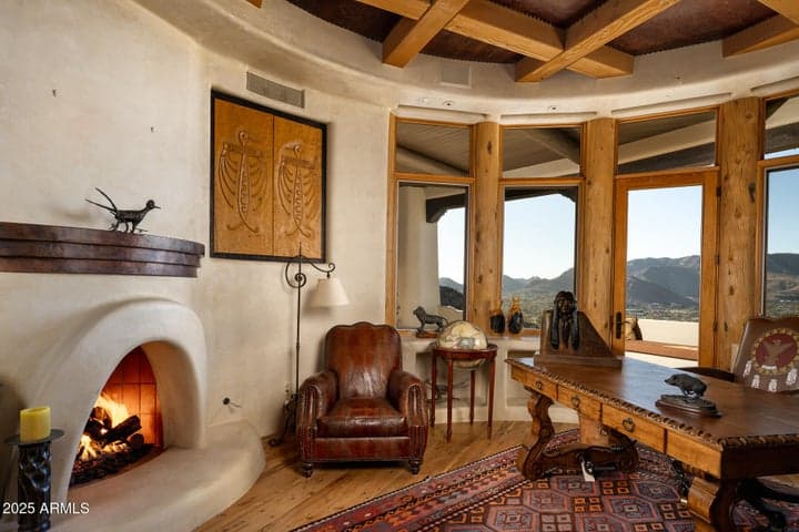 This custom office features a corner fireplace, handcrafted woodwork, and wraparound windows framing desert and city lights. Ideal for quiet focus or inspired creativity within this luxury Paradise Valley retreat.