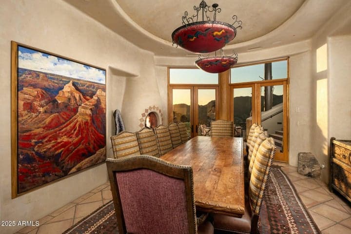This elegant dining room features access to a private patio, offering seamless indoor-outdoor living. Dramatic lighting, curved architecture, and expansive mountain views create a refined yet relaxed entertaining space